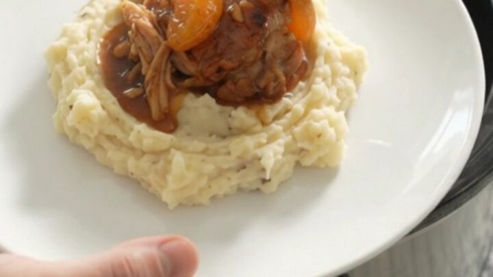 Slow cooker full of glazed chicken thighs with mandarin oranges and bourbon sauce, ready to serve