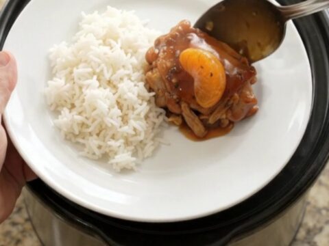 Slow-cooker chicken thighs in a glossy mandarin BBQ sauce, garnished with sesame seeds and green onions