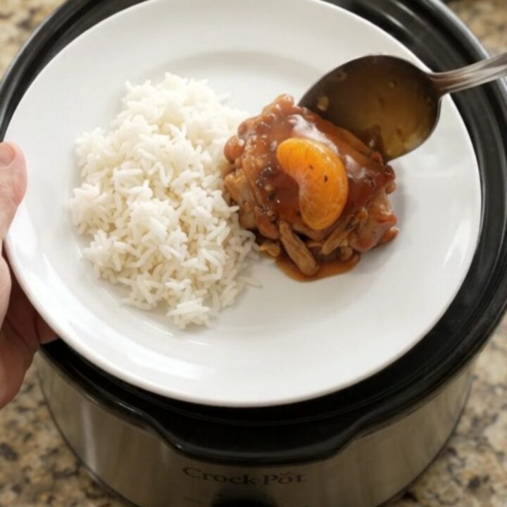 Slow-cooker chicken thighs in a glossy mandarin BBQ sauce, garnished with sesame seeds and green onions
