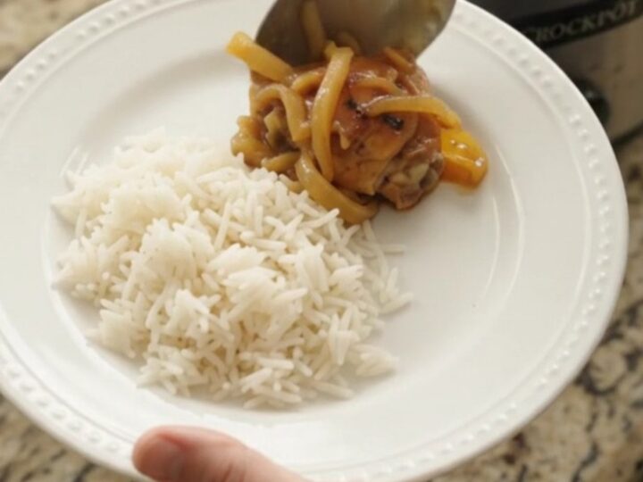 Caramelized pull-apart chicken thighs in a sticky apricot honey soy glaze, served in a black slow cooker.