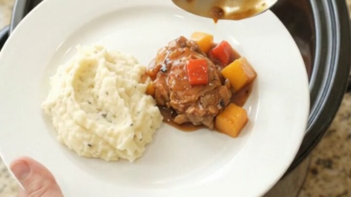 Slow cooker mango bourbon glazed chicken thighs in a glossy sauce with mango and red pepper