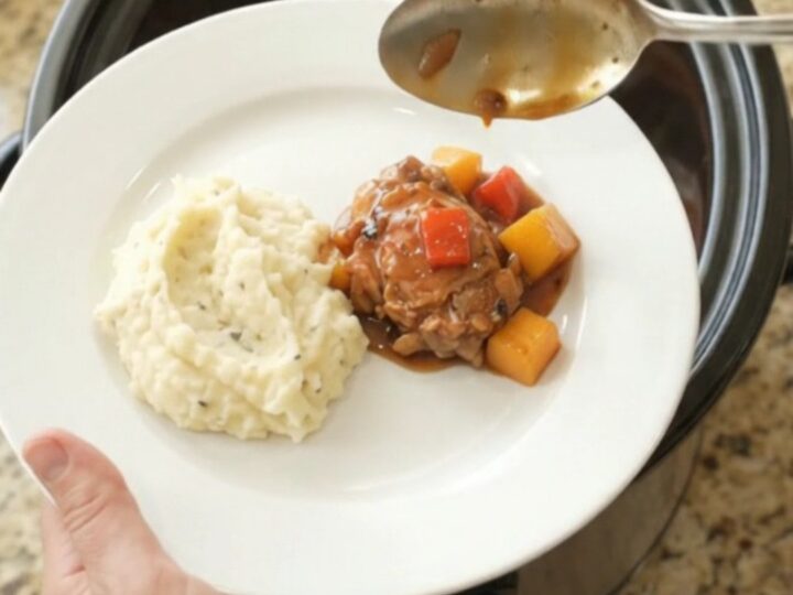 Slow cooker mango bourbon glazed chicken thighs in a glossy sauce with mango and red pepper