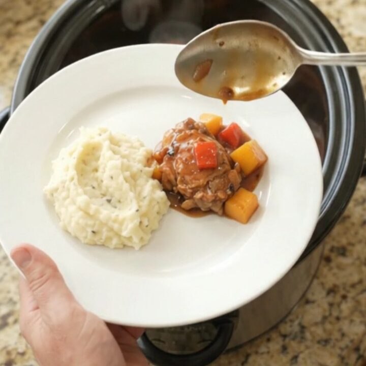 Slow cooker mango bourbon glazed chicken thighs in a glossy sauce with mango and red pepper