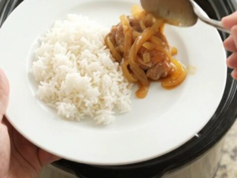 Shredded apricot teriyaki chicken thighs in a slow cooker, glazed and garnished with sesame seeds