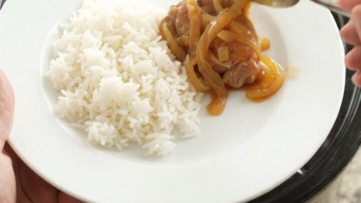Shredded apricot teriyaki chicken thighs in a slow cooker, glazed and garnished with sesame seeds