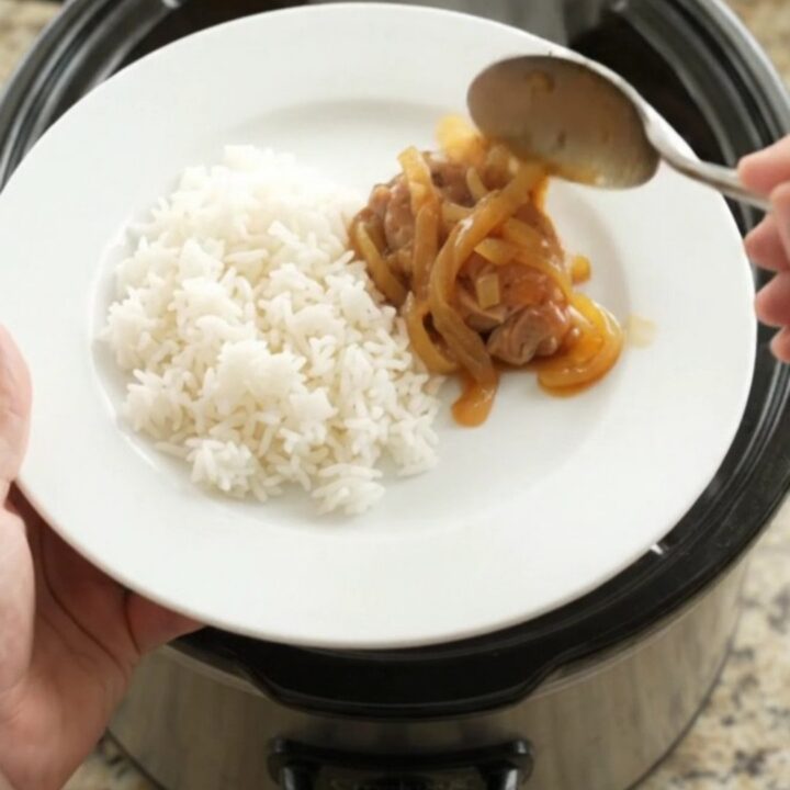 Shredded apricot teriyaki chicken thighs in a slow cooker, glazed and garnished with sesame seeds