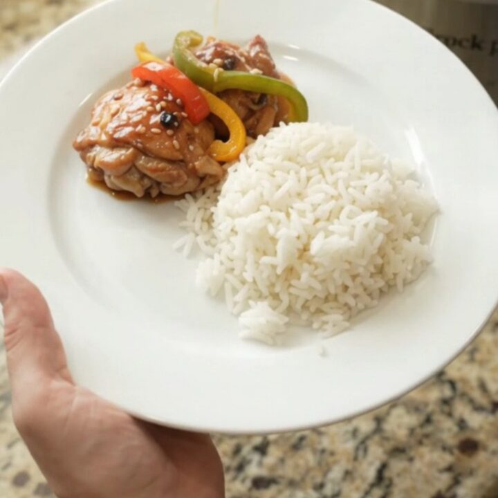 Slow cooker filled with teriyaki chicken thighs and bell peppers