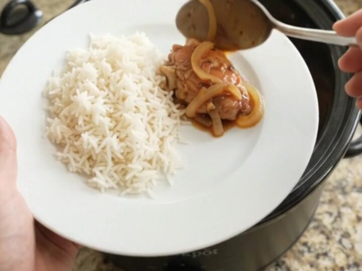 Slow cooker honey soy chicken thighs with caramelized onions in a black crock