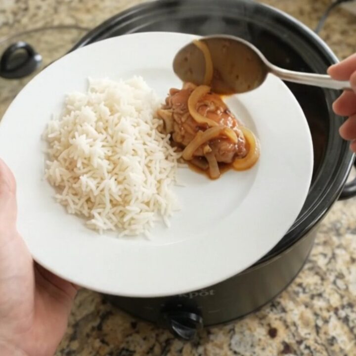 Slow cooker honey soy chicken thighs with caramelized onions in a black crock