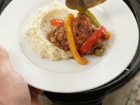 Slow cooker bourbon glazed chicken thighs with bell peppers and onion in a black crockpot