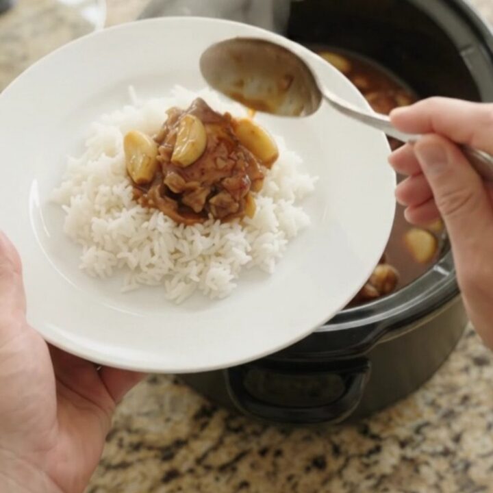 Pull-apart hickory BBQ chicken thighs with garlic and scallions in a slow cooker, glazed and steaming