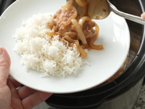 Caramelized chicken thighs with sweet Vidalia onions in a glossy teriyaki glaze, served in a black slow cooker.