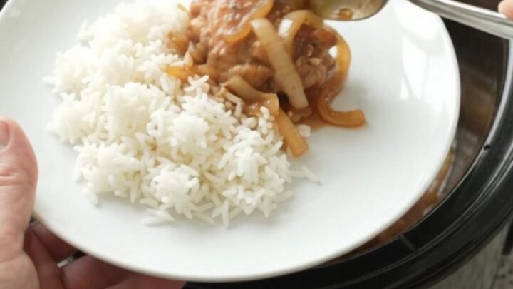 Caramelized chicken thighs with sweet Vidalia onions in a glossy teriyaki glaze, served in a black slow cooker.