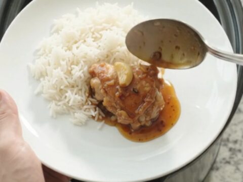 Caramelized honey soy chicken thighs in a slow cooker with whole garlic cloves and scallions