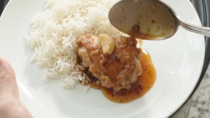 Caramelized honey soy chicken thighs in a slow cooker with whole garlic cloves and scallions