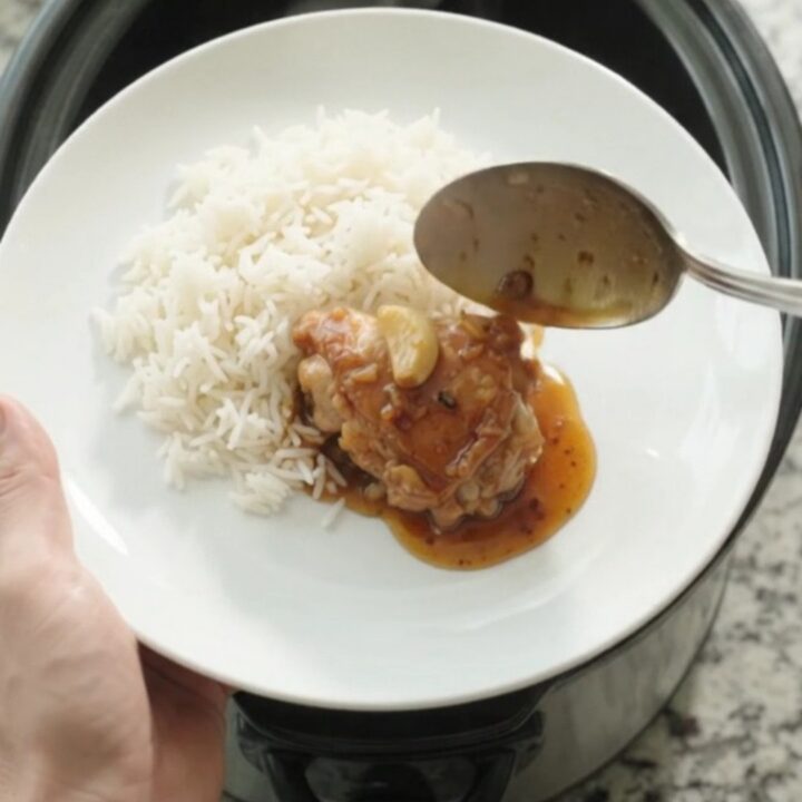 Caramelized honey soy chicken thighs in a slow cooker with whole garlic cloves and scallions