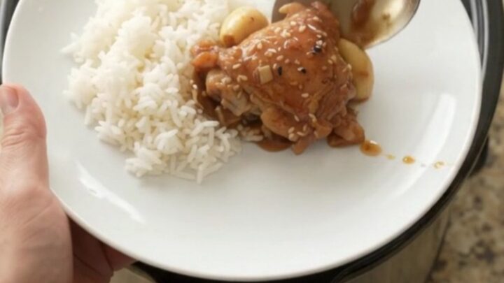 Shredded teriyaki chicken thighs with garlic and scallions in a slow cooker, glossy and caramelized.