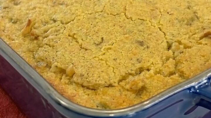 A warm scoop of cornbread chicken casserole with a cracked golden crust showing creamy chicken noodles and melted cheese.