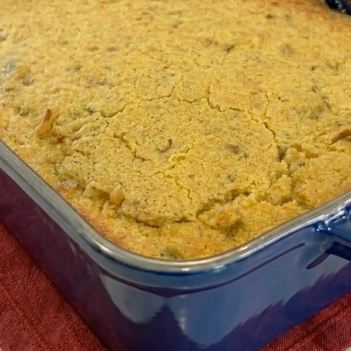 A warm scoop of cornbread chicken casserole with a cracked golden crust showing creamy chicken noodles and melted cheese.