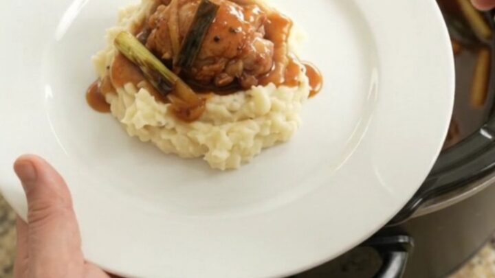 Pull-apart bourbon glazed chicken thighs in a slow cooker, glossy sauce with ginger and scallions