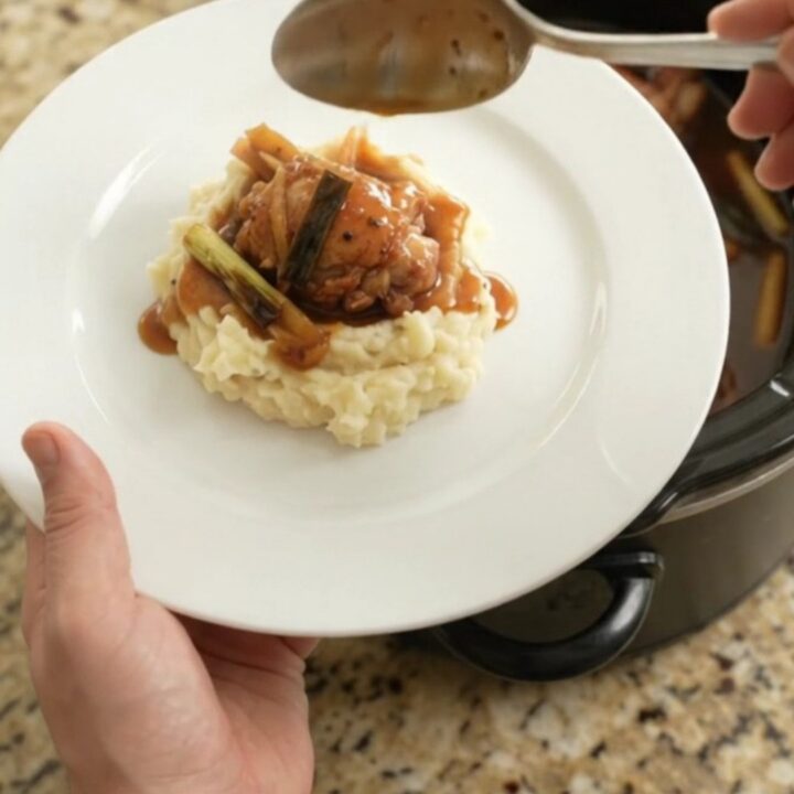 Pull-apart bourbon glazed chicken thighs in a slow cooker, glossy sauce with ginger and scallions