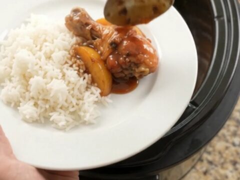 Glazed chicken drumsticks with peach slices in a slow cooker, bubbling in hickory BBQ sauce
