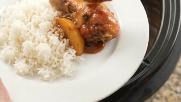 Glazed chicken drumsticks with peach slices in a slow cooker, bubbling in hickory BBQ sauce