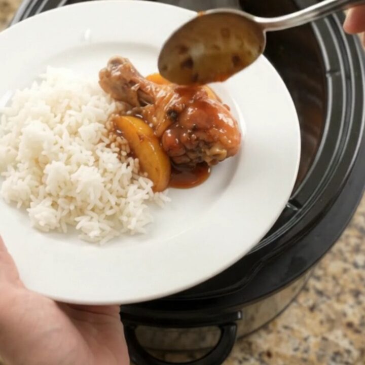 Glazed chicken drumsticks with peach slices in a slow cooker, bubbling in hickory BBQ sauce