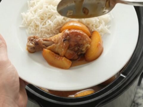 Slow cooker peach honey soy chicken drumsticks glazed and sticky in a black crockpot