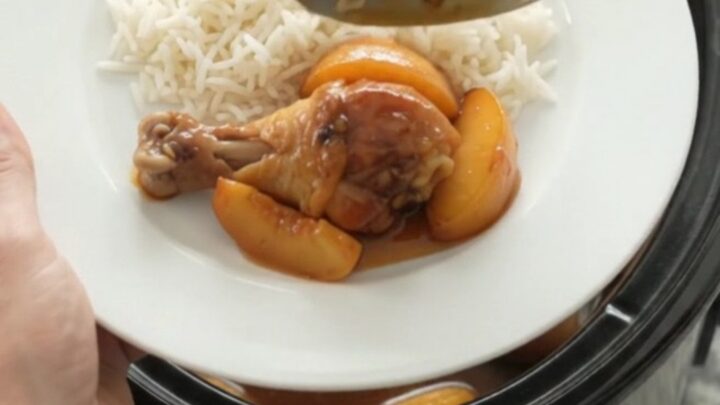 Slow cooker peach honey soy chicken drumsticks glazed and sticky in a black crockpot