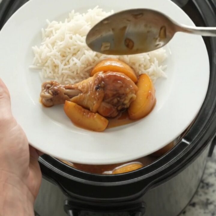 Slow cooker peach honey soy chicken drumsticks glazed and sticky in a black crockpot