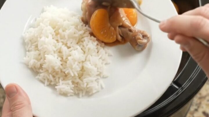 Slow cooker full of glazed chicken drumsticks with mandarin oranges and sesame seeds.