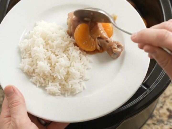 Slow cooker full of glazed chicken drumsticks with mandarin oranges and sesame seeds.
