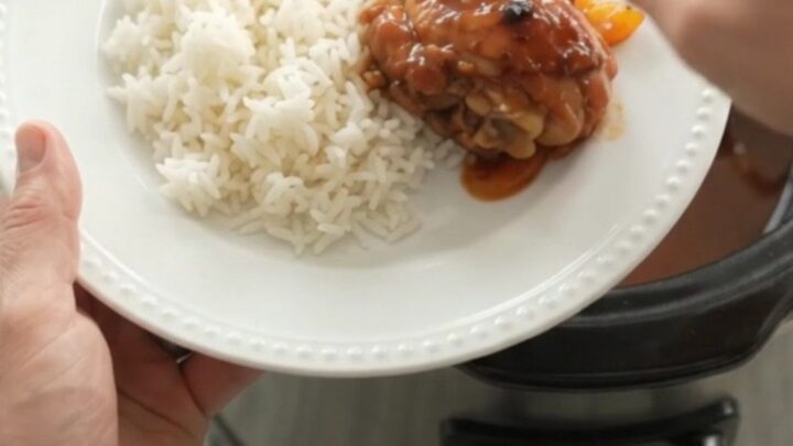 Slow cooker hickory BBQ chicken drumsticks with bell peppers and onions in a dark crockpot.
