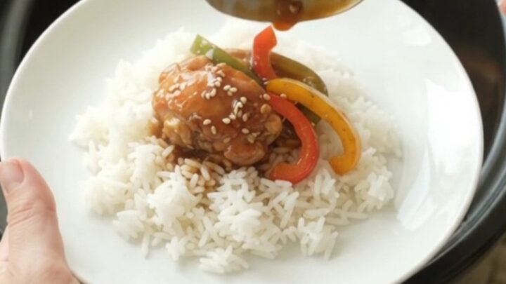 Glossy teriyaki chicken drumsticks on a white platter, garnished with sesame seeds and green onions.