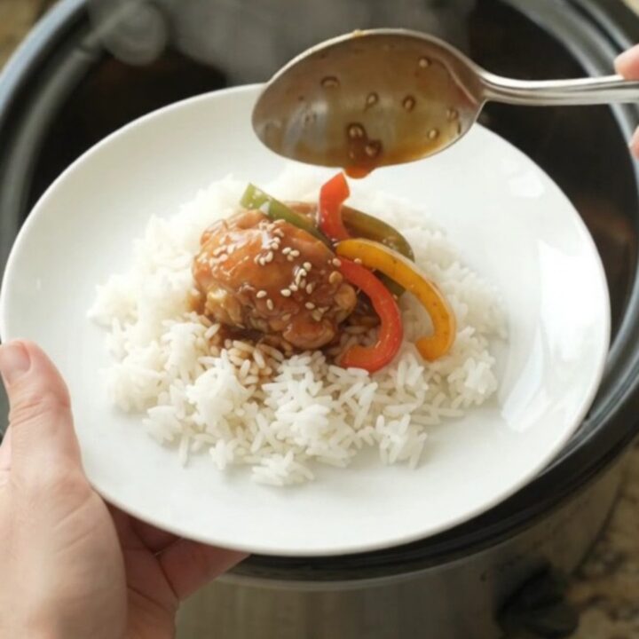 Glossy teriyaki chicken drumsticks on a white platter, garnished with sesame seeds and green onions.