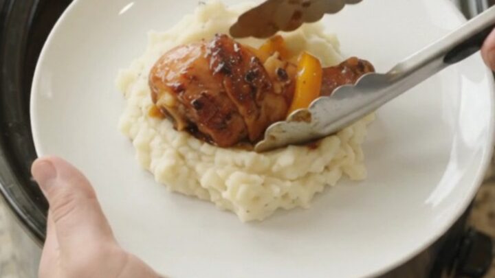 Slow cooker bourbon glazed chicken drumsticks with bell peppers in a glossy black crockpot