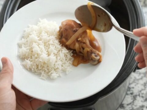 Glazed chicken drumsticks in a slow cooker with caramelized onions and sesame seeds