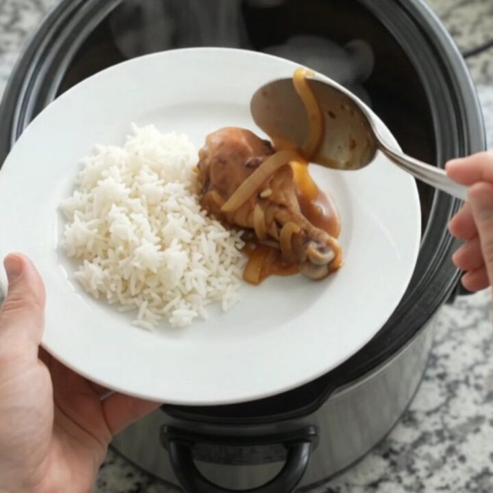 Glazed chicken drumsticks in a slow cooker with caramelized onions and sesame seeds