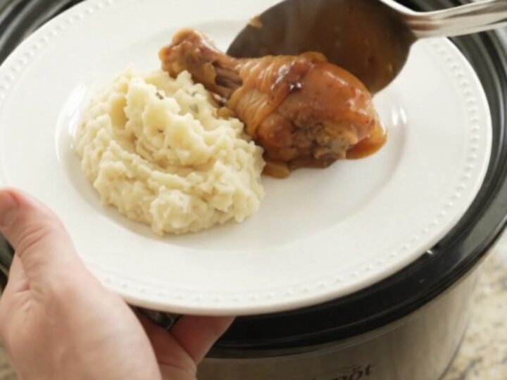 Slow cooker bourbon glazed chicken drumsticks with caramelized Vidalia onions in a black crockpot