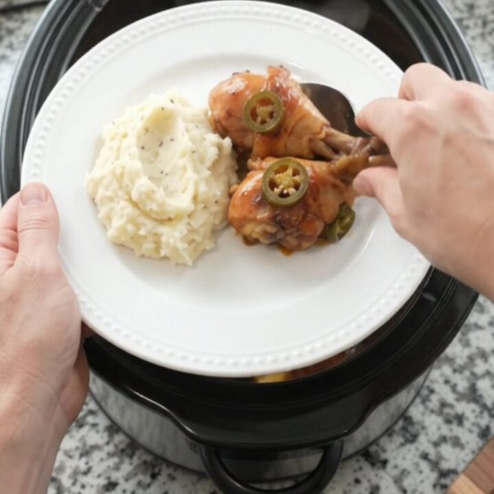A slow cooker filled with glazed chicken drumsticks, pineapple, and jalapeños