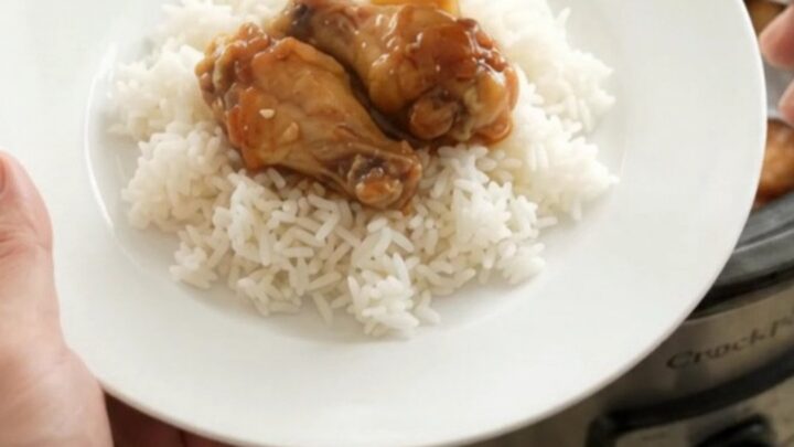 Slow-cooker pineapple teriyaki chicken wings in a black Crockpot, glossy with sauce and sprinkled with sesame seeds.