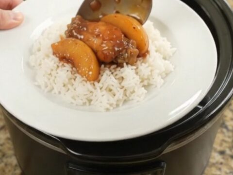 Slow cooker chicken wings with peaches and BBQ sauce, glistening in the pot