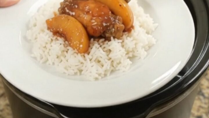 Slow cooker chicken wings with peaches and BBQ sauce, glistening in the pot