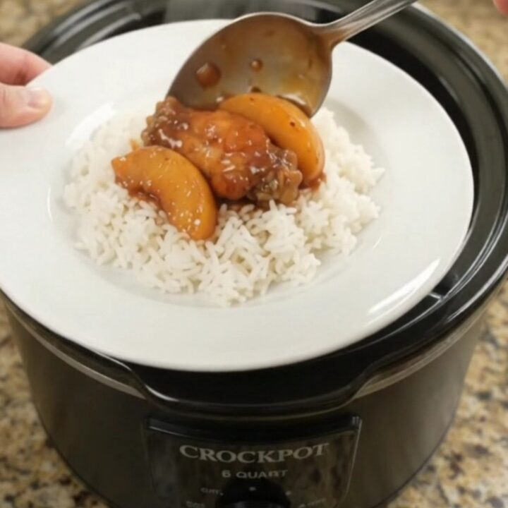 Slow cooker chicken wings with peaches and BBQ sauce, glistening in the pot