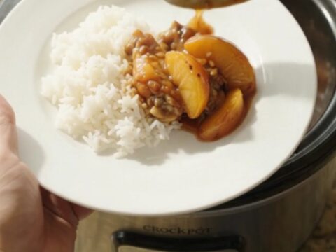 Glazed chicken wings and peach slices in a slow cooker with teriyaki sauce