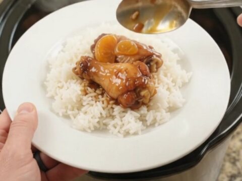 Sticky slow cooker chicken wings with mandarin oranges in a glossy BBQ glaze, served on a white plate.