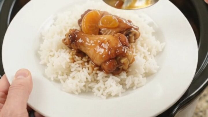 Sticky slow cooker chicken wings with mandarin oranges in a glossy BBQ glaze, served on a white plate.