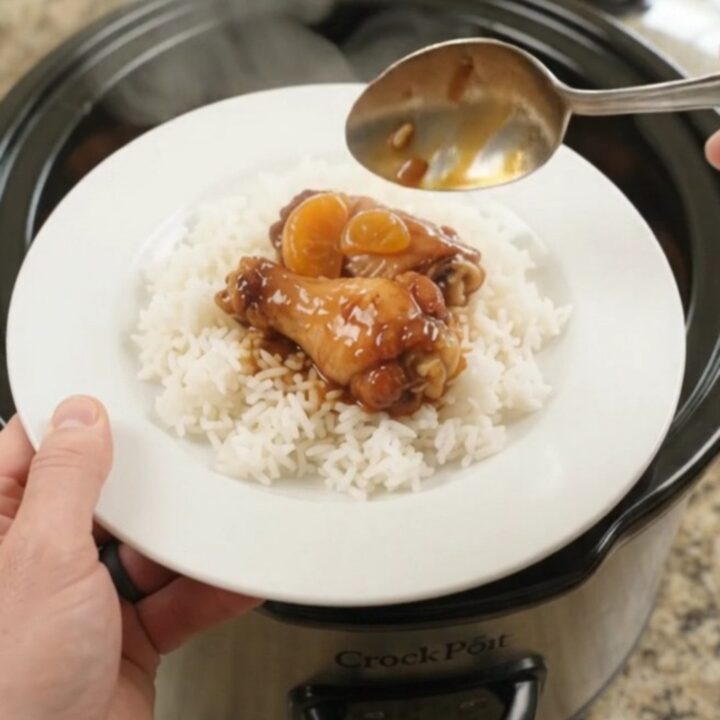 Sticky slow cooker chicken wings with mandarin oranges in a glossy BBQ glaze, served on a white plate.