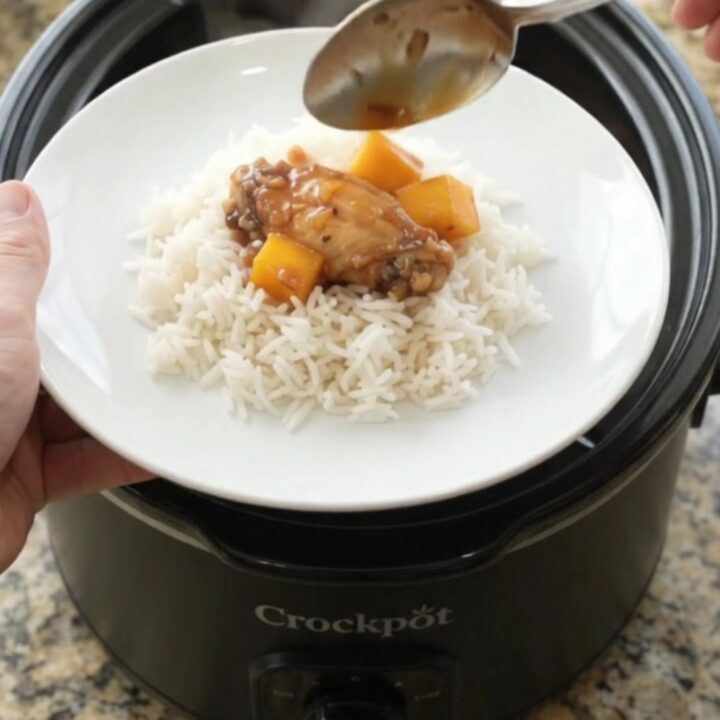 Sticky mango honey soy chicken wings in a slow cooker, glistening with sauce and garnished with mango cubes and red peppers.